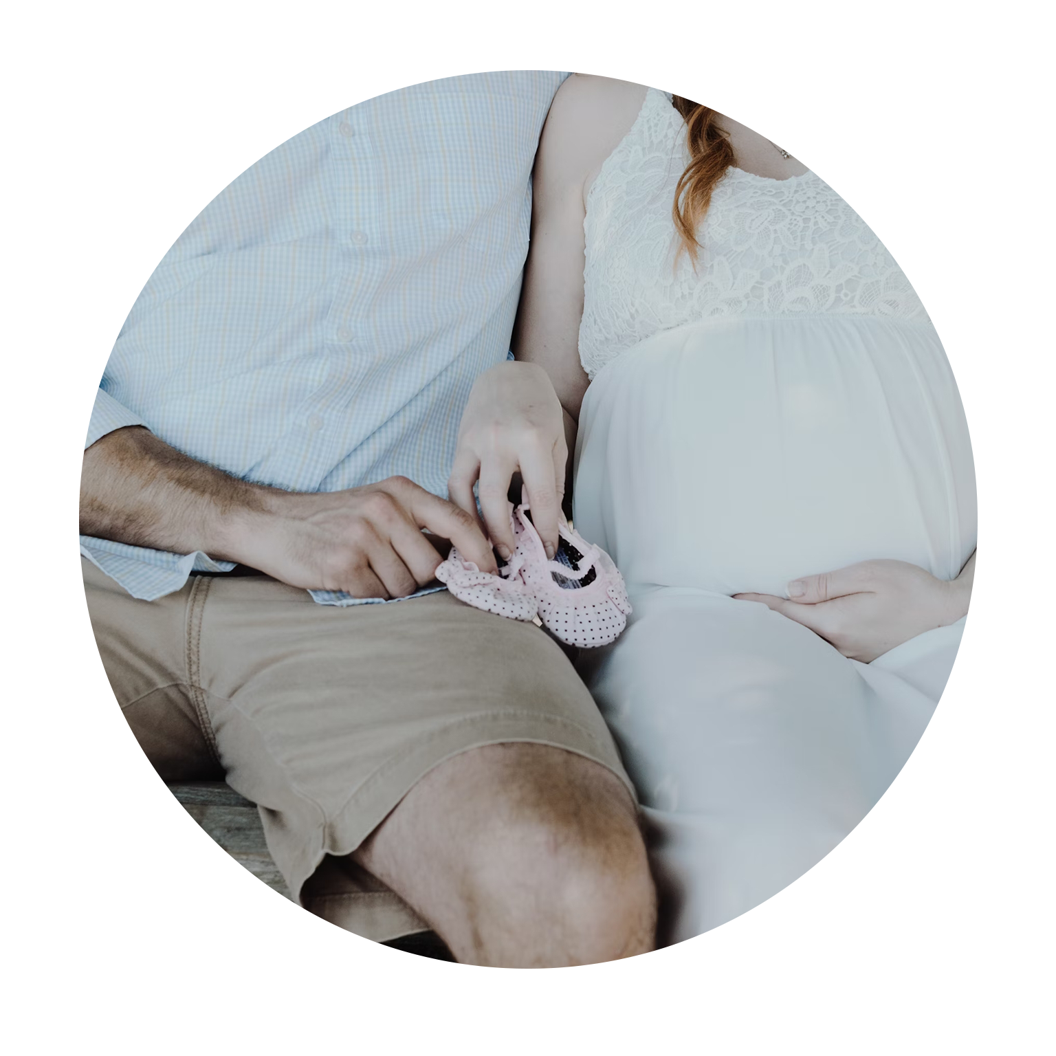 Expecting couple with baby shoes, hinting at parental transition.
